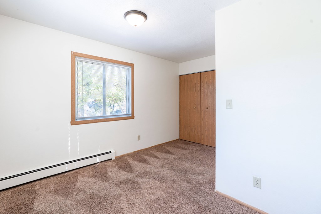 A room with a window and carpeted floor. Fargo, ND Morningside Apartments