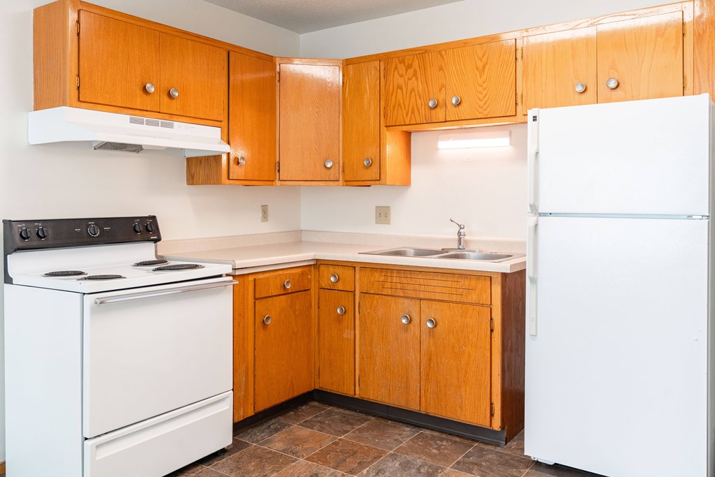 A kitchen with wooden cabinets and a white refrigerator. Fargo, ND Morningside Apartments