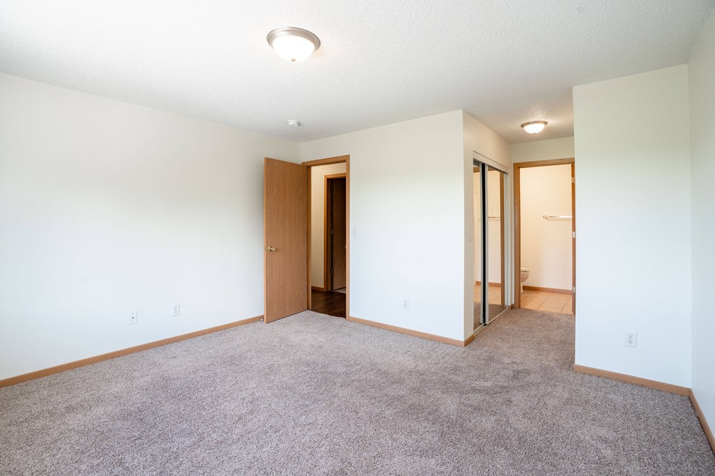 A room with a carpeted floor and a ceiling light. Bismarck, ND Sierra Ridge Apartments
