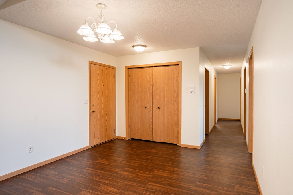 A hallway with wood floors and two doors. Bismarck, ND Sierra Ridge Apartments