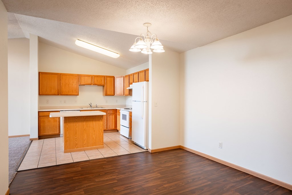 A kitchen with wooden cabinets and a white refrigerator. Bismarck, ND Sierra Ridge Apartments