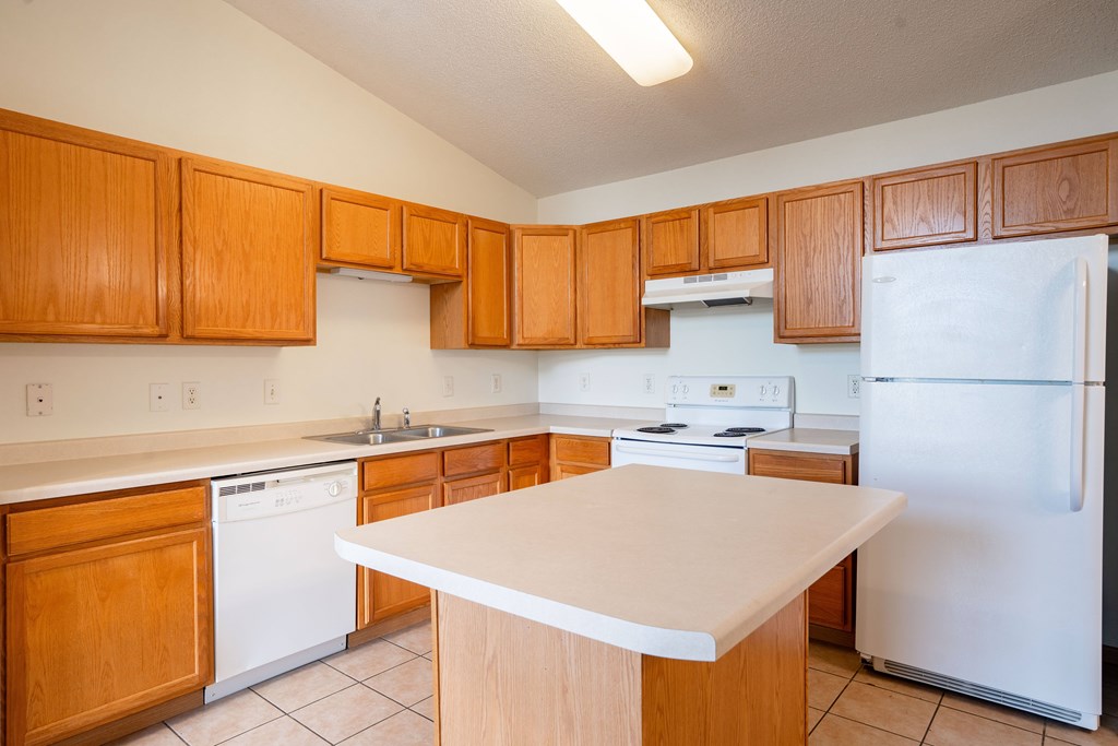 A kitchen with wooden cabinets and white appliances. Bismarck, ND Sierra Ridge Apartments
