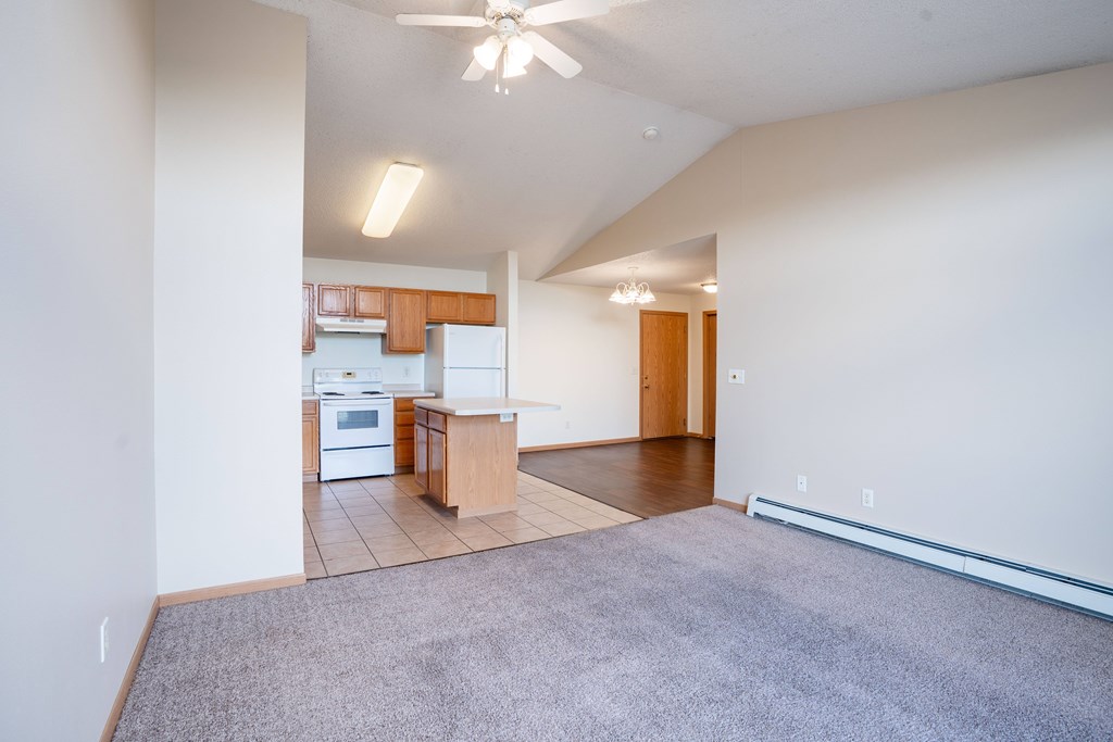 A spacious living room with a kitchen in the background. Bismarck, ND Sierra Ridge Apartments