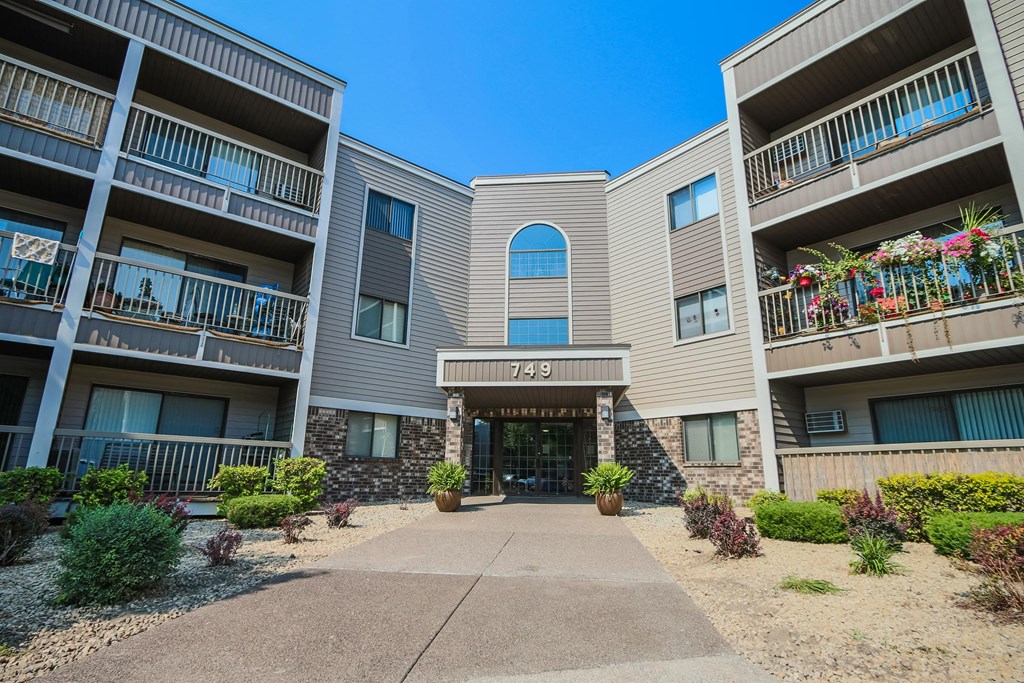 an exterior view of an apartment building with a sidewalk and potted plants