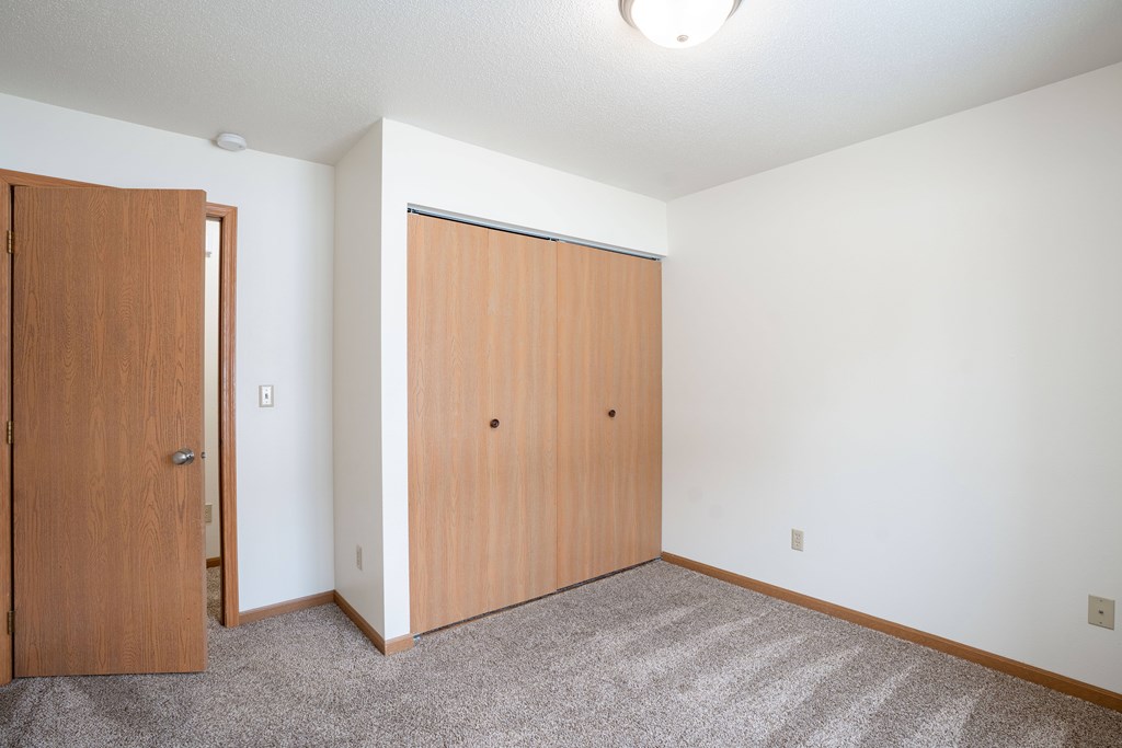 A room with two doors and a carpeted floor. Fargo, ND Long Island Apartments