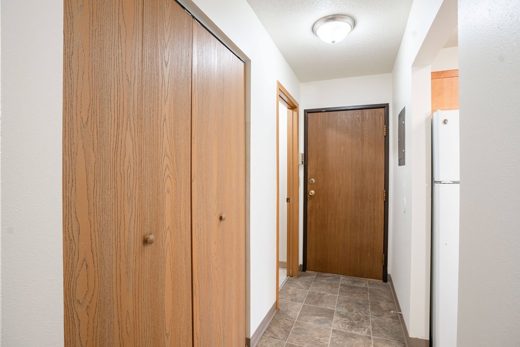 A hallway with a wooden door on the left and a brown door on the right. Fargo, ND Long Island Apartments