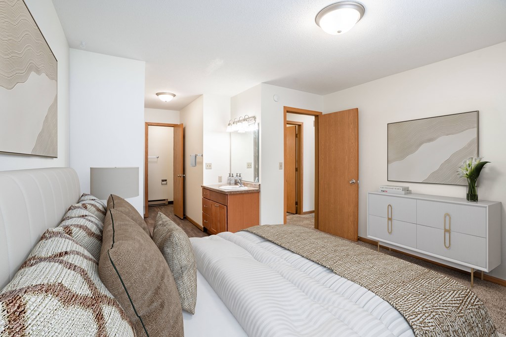 A bedroom with a large bed and a television. Fargo, ND Long Island Apartments