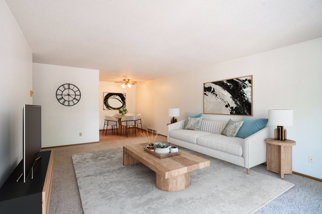 A living room with a white couch and a wooden coffee table. Fargo, ND West Oak Apartments