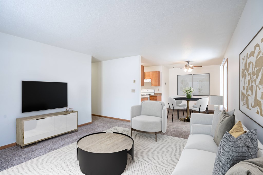 A living room with a television, a sofa, a chair, a table, and a cabinet. Fargo, ND Long Island Apartments