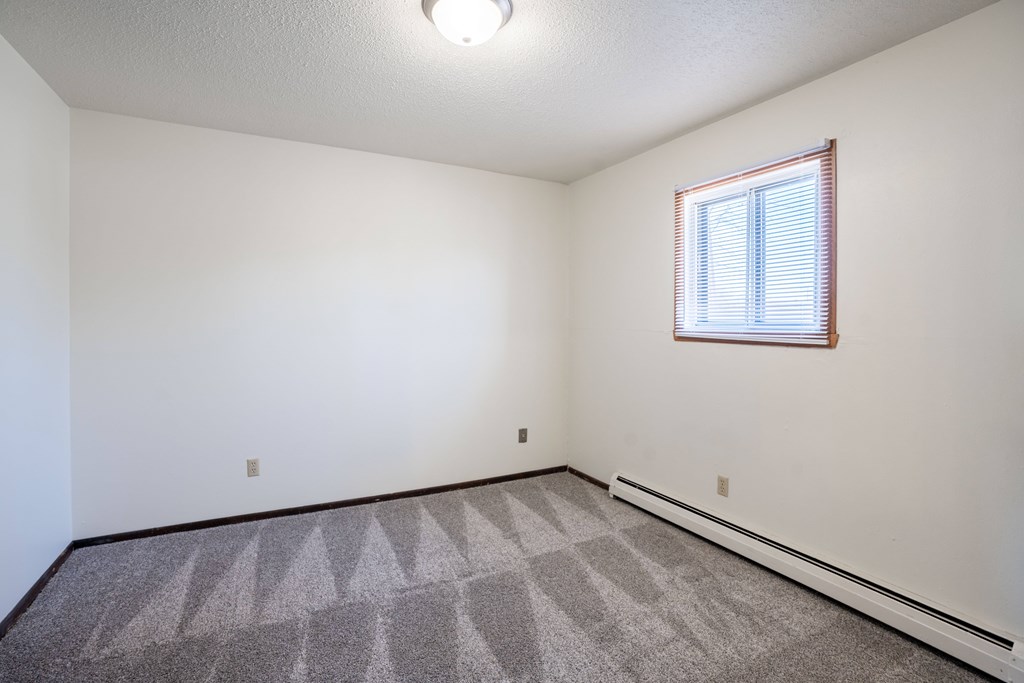 A room with a window and a carpeted floor. West Fargo, ND Parkwest Gardens
