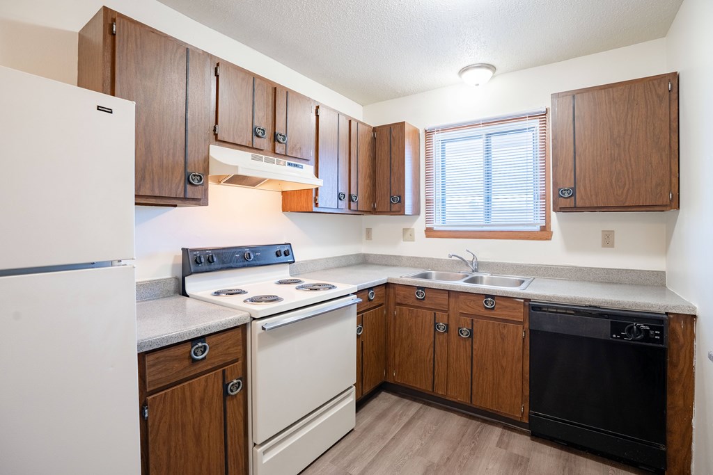 A kitchen with wooden cabinets and a white refrigerator. West Fargo, ND Parkwest Gardens
