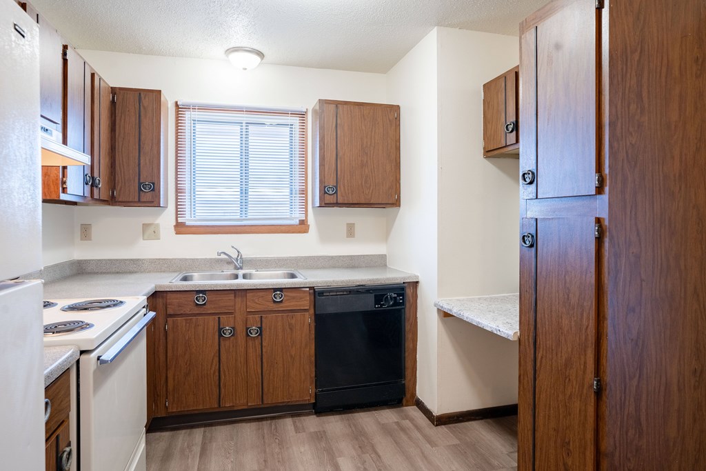 A kitchen with wooden cabinets and a black dishwasher. West Fargo, ND Parkwest Gardens
