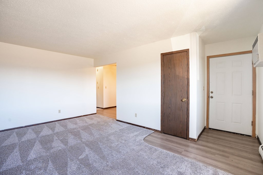 A room with a carpet and a brown door. West Fargo, ND Parkwest Gardens