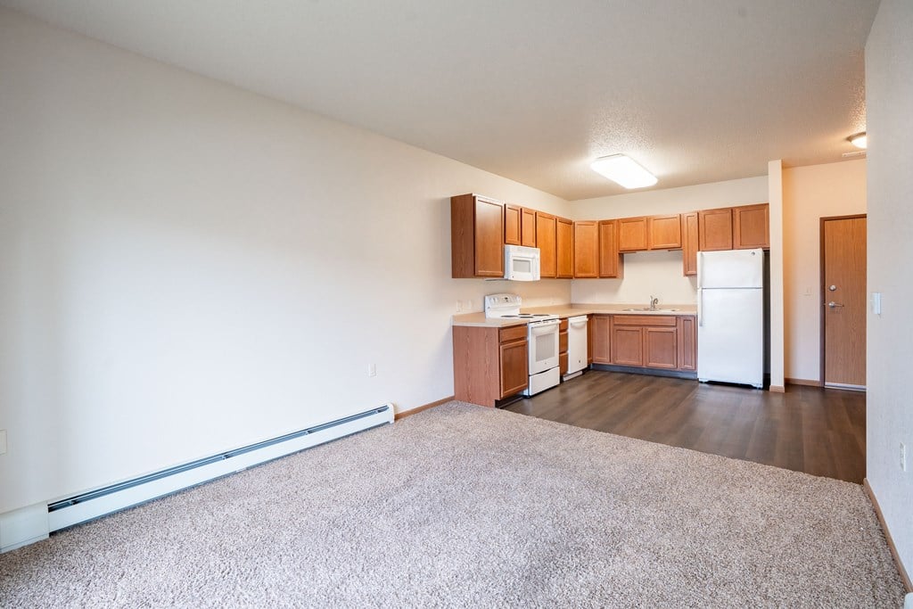 A kitchen with white appliances and wooden cabinets. Fargo, ND North Sky II Apartments