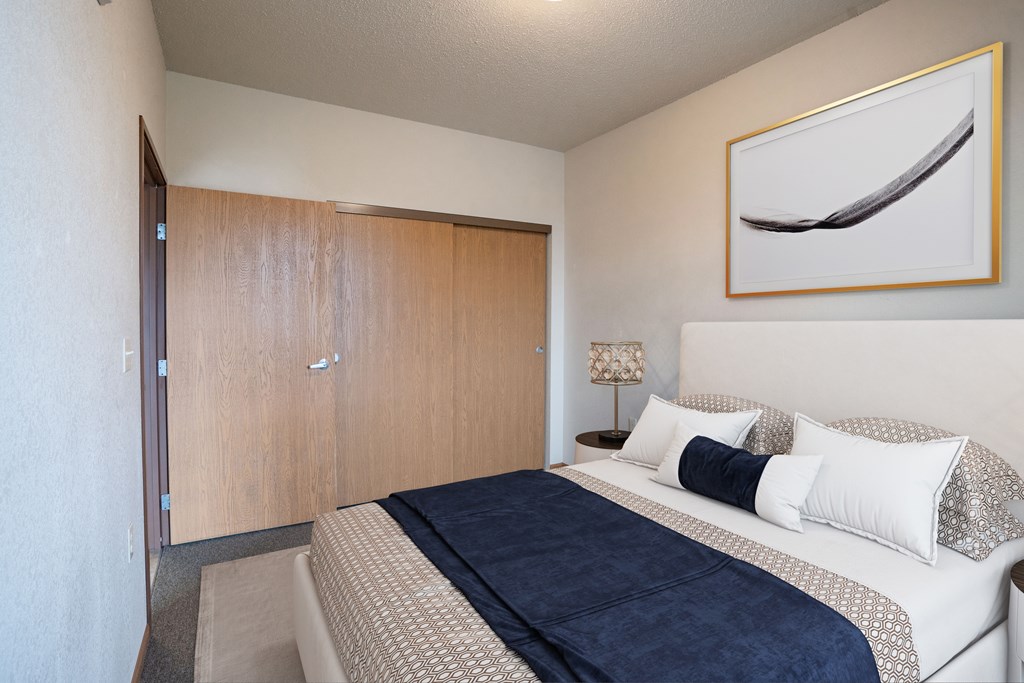 A bedroom with a bed, pillows, and a painting on the wall.