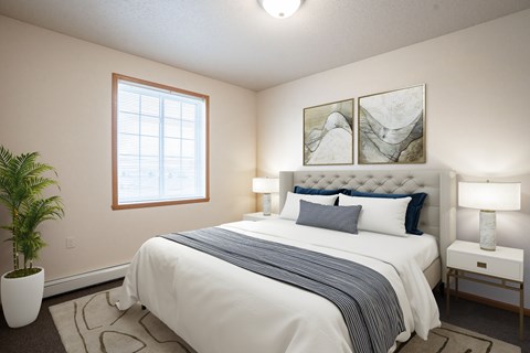 A bedroom with a large bed, a potted plant, and two framed pictures on the wall.