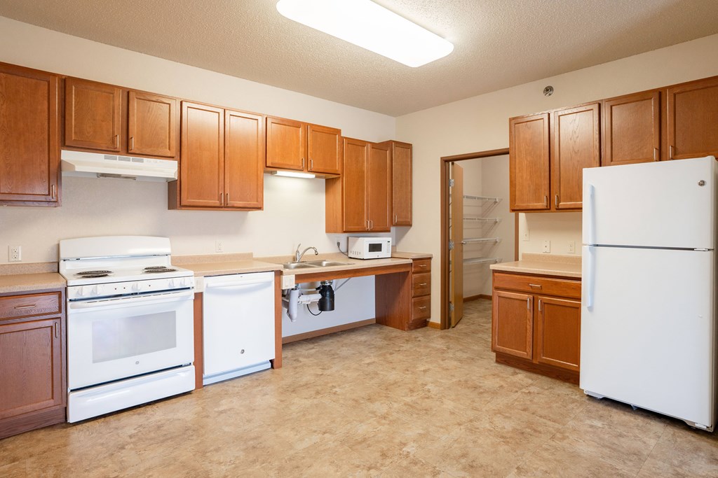 A kitchen with white appliances and wooden cabinets. Fargo, ND North Sky II Apartments