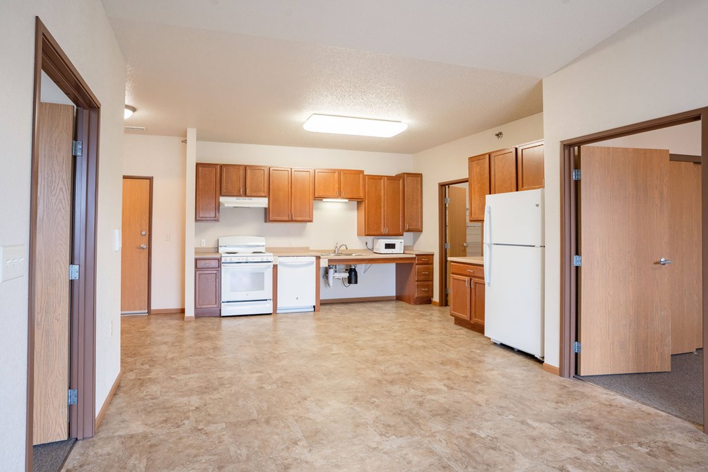 A kitchen with brown cabinets and a white refrigerator. Fargo, ND North Sky II Apartments