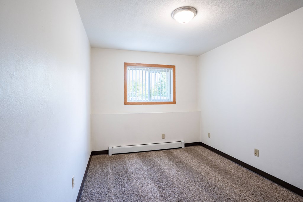 A room with a window and a carpeted floor. Fargo, ND Islander Apartments