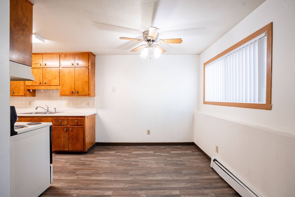 A kitchen with wooden cabinets and a ceiling fan. Fargo, ND Islander Apartments