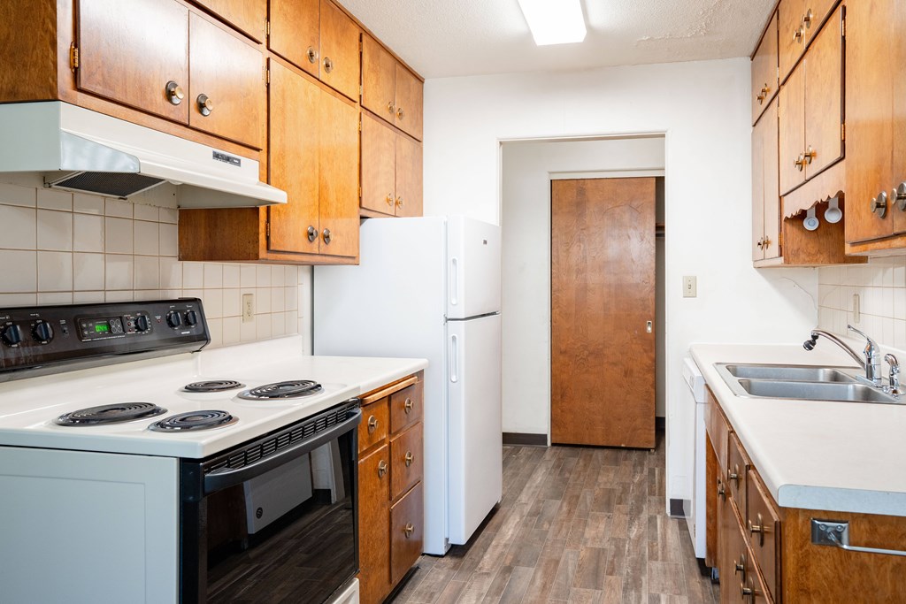 A kitchen with wooden cabinets and a white stove top oven. Fargo, ND Islander Apartments