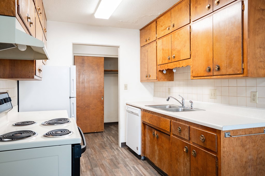 A kitchen with wooden cabinets and a white counter top. Fargo, ND Islander Apartments