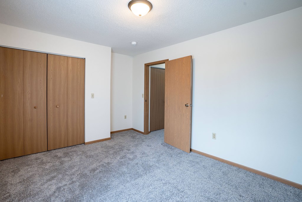 A room with a carpeted floor and a door. Fargo, ND Hazelwood Townhomes