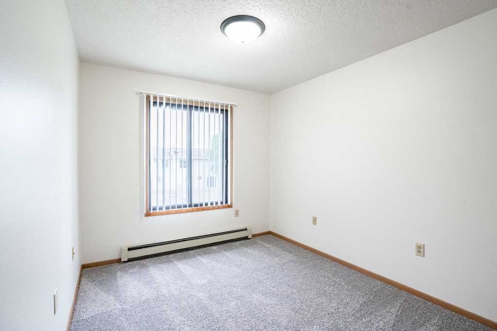 A room with a window and a carpeted floor. Fargo, ND Hazelwood Townhomes