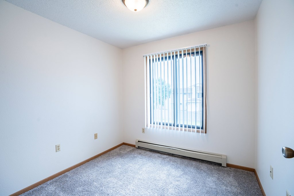 A room with a window and a carpet on the floor. Fargo, ND Hazelwood Townhomes
