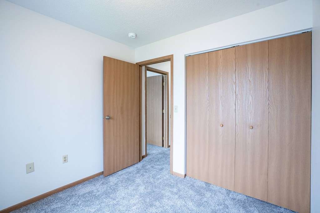 A room with a carpeted floor and  a closet. Fargo, ND Hazelwood Townhomes