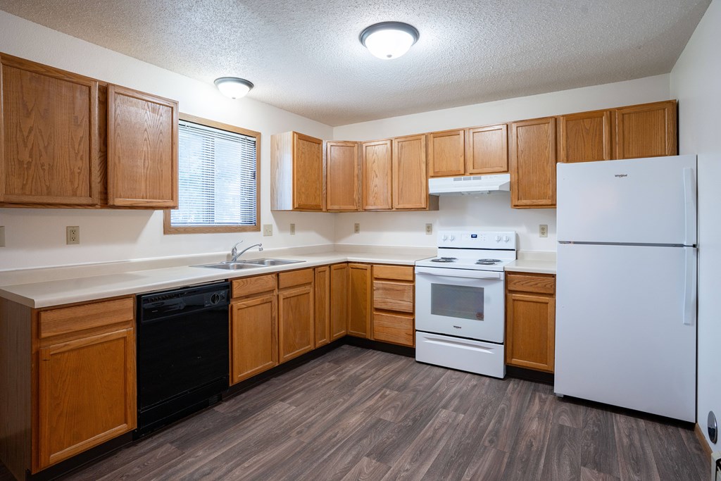 A kitchen with wooden cabinets and white appliances. Fargo, ND Hazelwood Townhomes