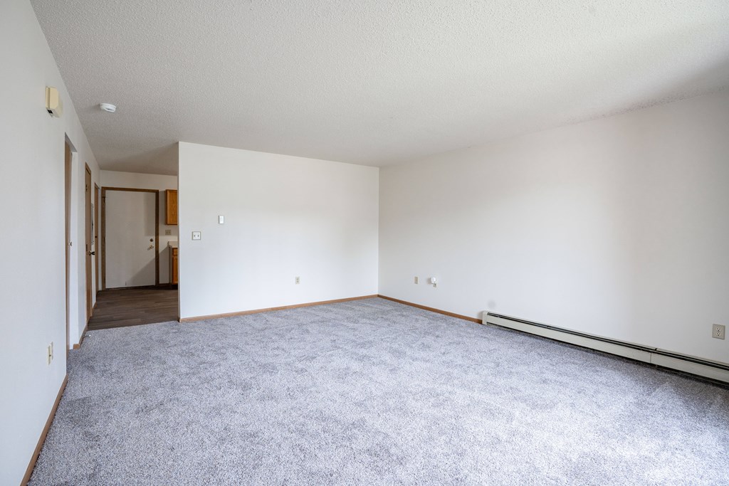 A large empty room with a carpeted floor and white walls. Fargo, ND Hazelwood Townhomes
