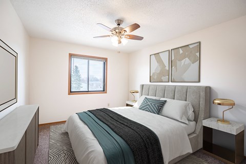 A bedroom with a bed, nightstand, and window. Fargo, ND Hawthorn Apartments