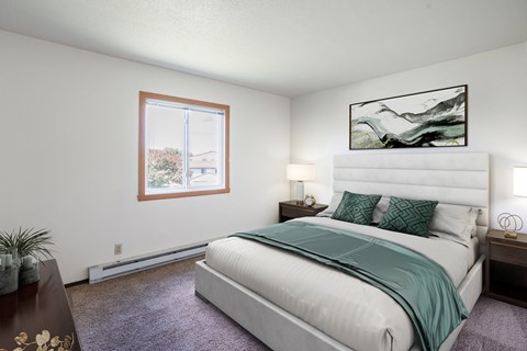 A bedroom with a large bed and a painting on the wall. Fargo, ND Summerfield Apartments