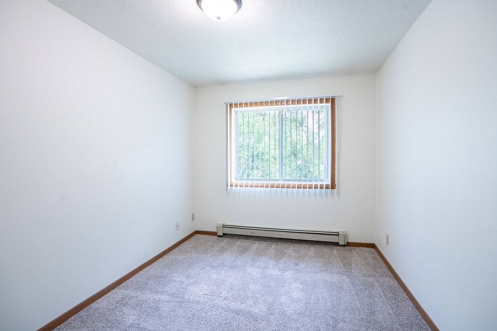 A room with a window and a carpet on the floor. Grand Forks, ND Columbia West Apartments