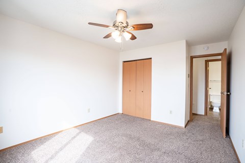A room with a ceiling fan and a carpeted floor. Fargo, ND Hawthorn Apartments