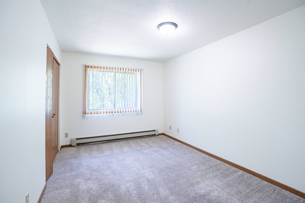 A room with a window and a carpeted floor. Grand Forks, ND Columbia West Apartments