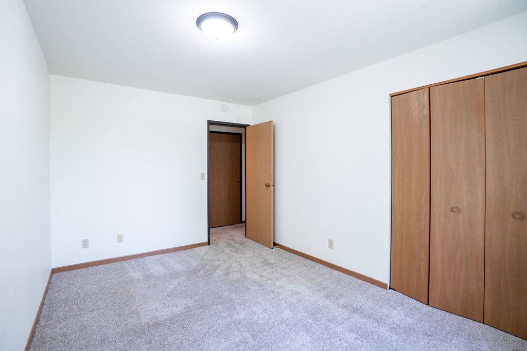 A room with a carpeted floor and two wooden doors. Grand Forks, ND Columbia West Apartments
