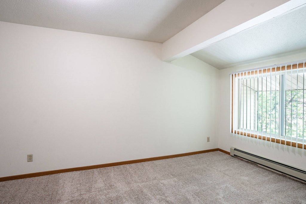 A room with a window and a carpeted floor. Grand Forks, ND Columbia West Apartments