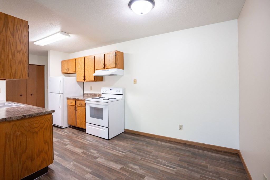 A kitchen with white appliances and wooden cabinets. Grand Forks, ND Columbia West Apartments