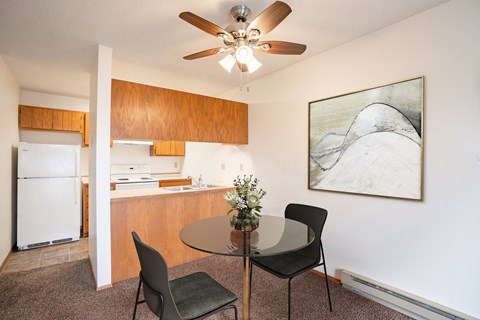 A kitchen with a table and chairs and a ceiling fan. Fargo, ND Hawthorn Apartments