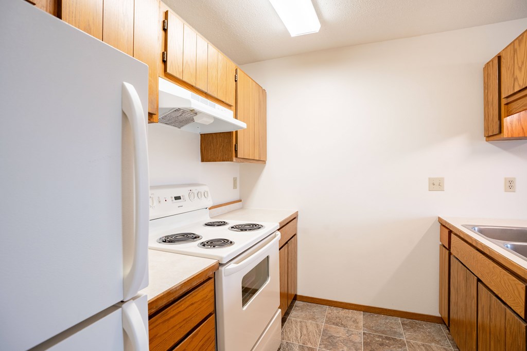 A kitchen with a white refrigerator and white stove. Fargo, ND Hawthorn Apartments
