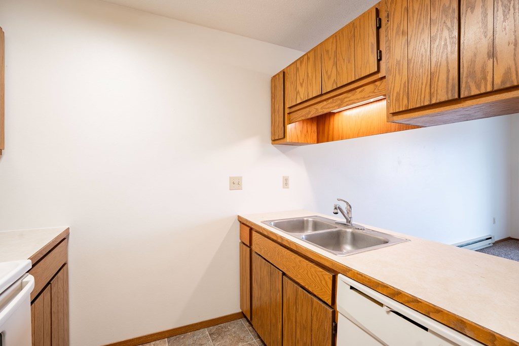 A kitchen with wooden cabinets and a white countertop. Fargo, ND Hawthorn Apartments