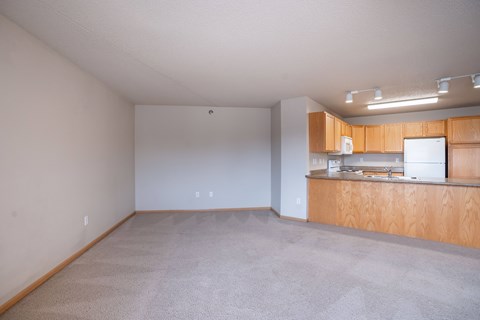 Empty room with a kitchenette and carpeted floor. Fargo, ND East Bridge Apartments