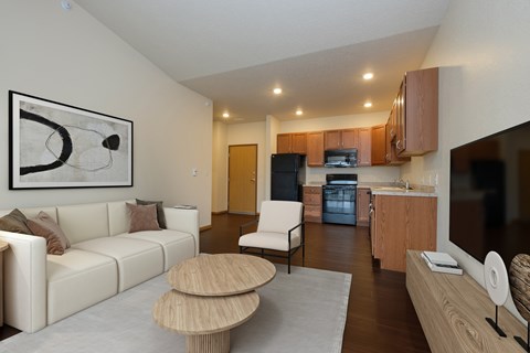 A modern living room with a white couch, wooden coffee table, and a painting on the wall.