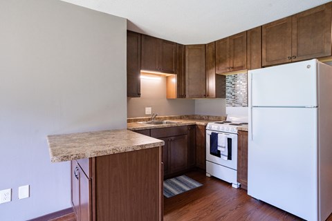 A kitchen with a white refrigerator and wooden cabinets.