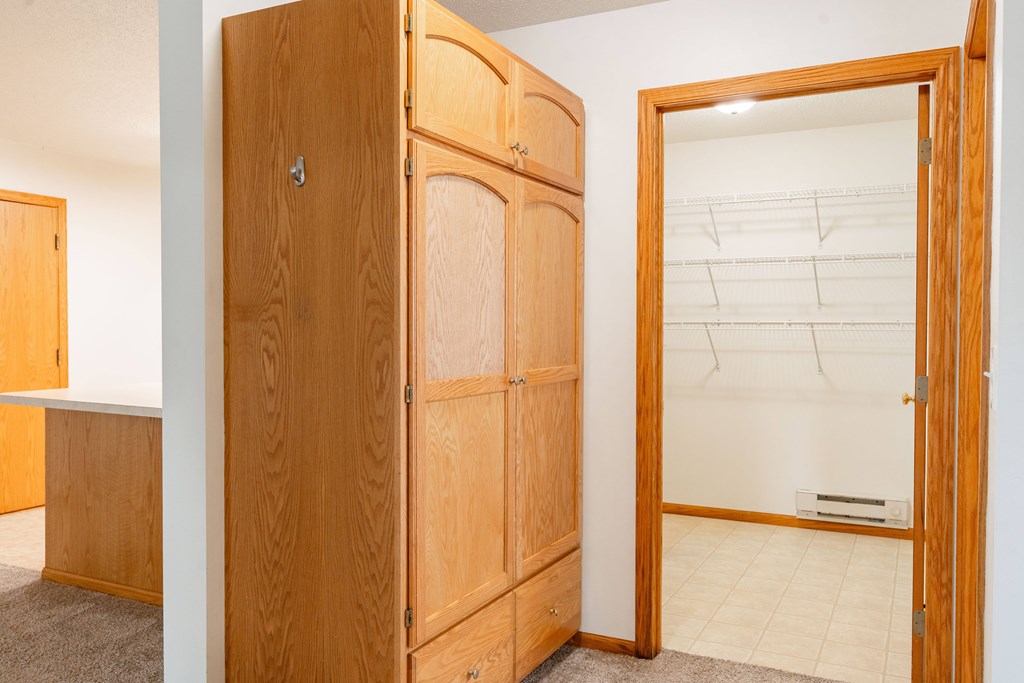 A wooden wardrobe with a mirror on the door stands in a room. Fargo, ND Crown Court 2 Apartments