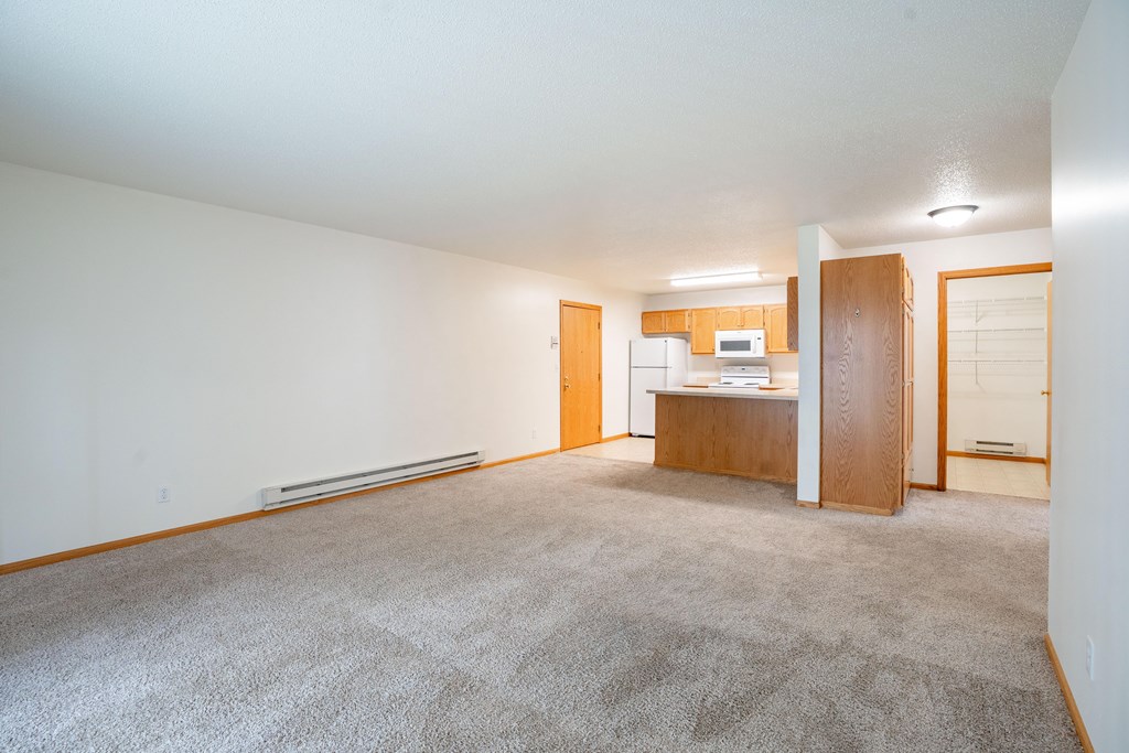 A carpeted room with a desk and a refrigerator. Fargo, ND Crown Court 2 Apartments