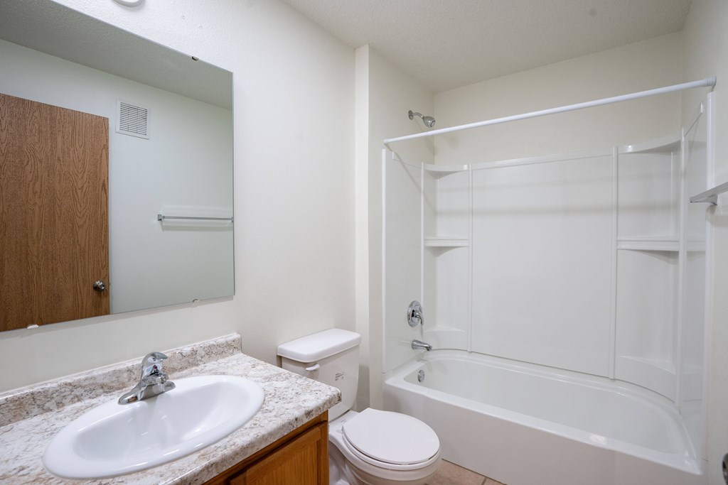A white bathroom with a sink, toilet, and bathtub. Bismarck, ND Sierra Ridge Apartments