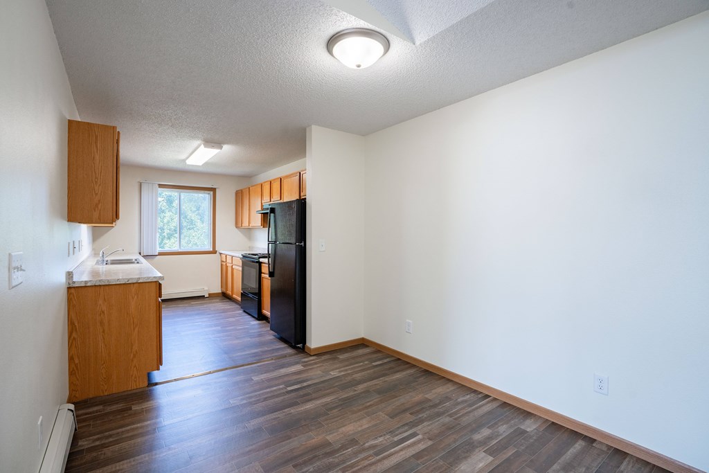 A kitchen with a refrigerator, sink, and cabinets. Bismarck, ND Sierra Ridge Apartments